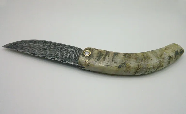 Couteau corse Manu Padovani ouvert, lame damas carbone de 10 cm et manche courbé en corne de bélier. padovani-curnichjiolu-belier-damas-ouvert-dos.webp