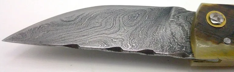 Gros plan sur les motifs de la lame en acier Damas du couteau corse Padovani couteau-corse-padovani-detail-acier-damas-08.webp
