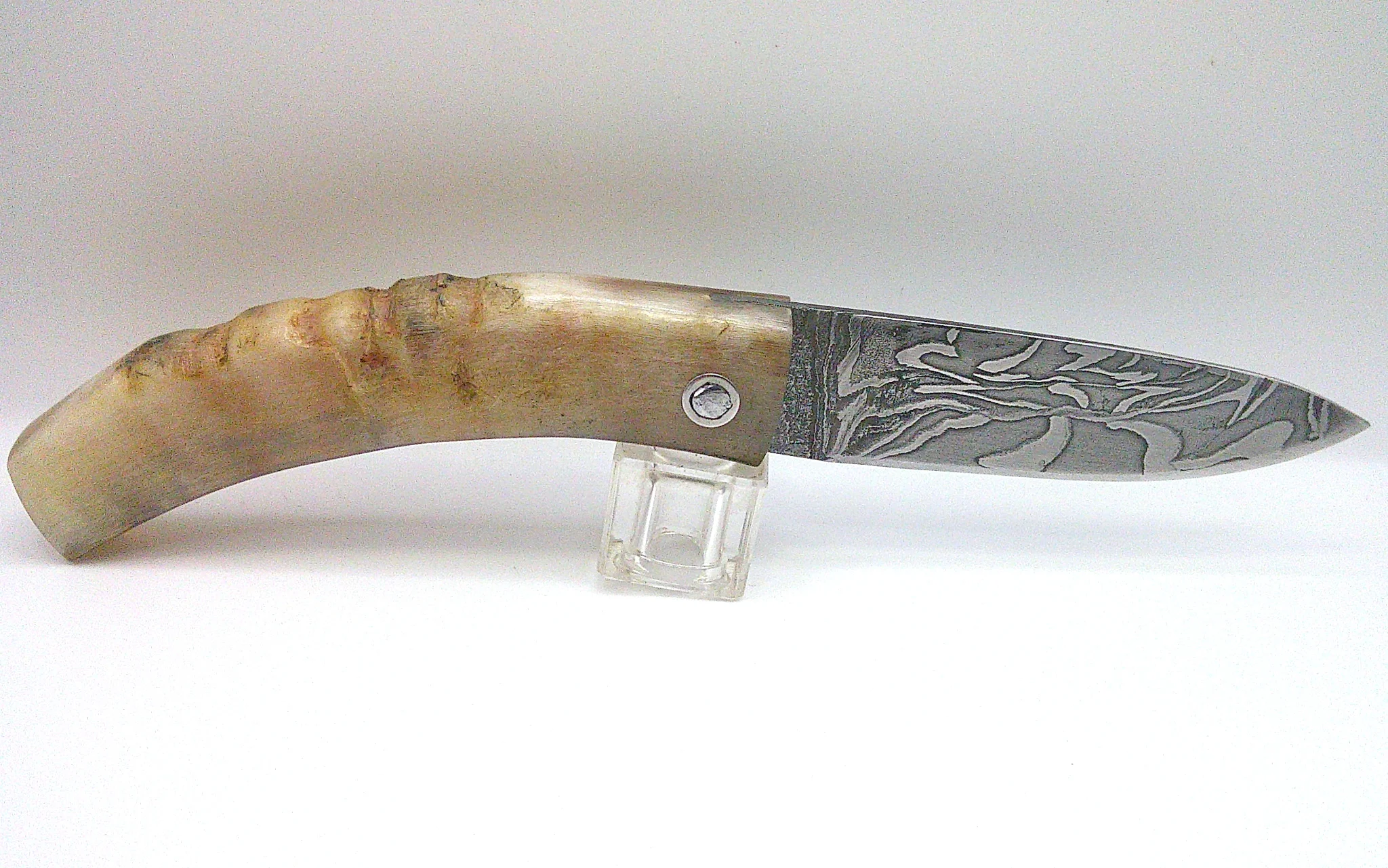 Vue supérieure du couteau corse artisanal Curnichjiolu Padovani ouvert, motifs damassés de la lame et courbure du manche en corne blonde.